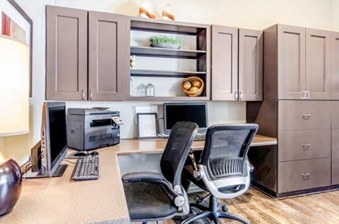 A kitchen with brown cabinets and a desk with a computer and chair.