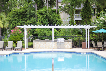 an outdoor kitchen next to a pool with a pergola