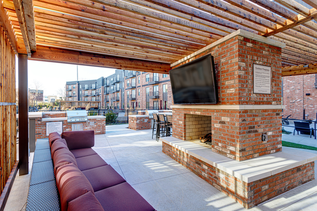 a patio with a brick fireplace and a tv on top of it