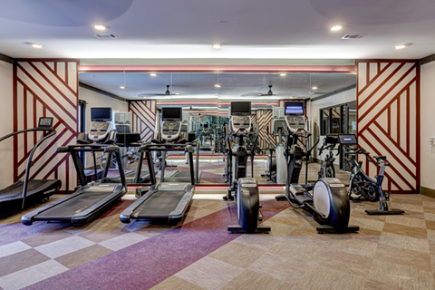 a gym with treadmills and other exercise equipment in a room with a projector