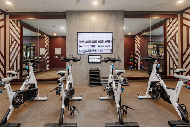 a gym with exercise bikes and a tv on the wall