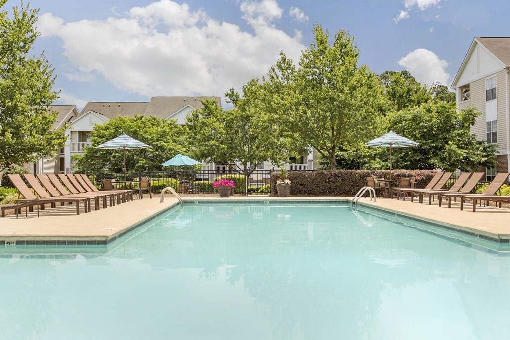Swimming Pool and Sun Deck with Lounge Chairs with Trees and Building Exteriors in the Background at The Grayson Apartment Homes, Charlotte, North Carolina