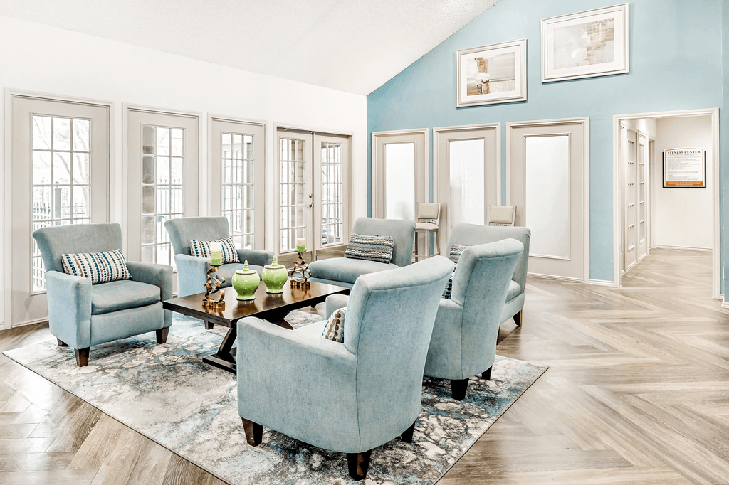 Clubhouse interior with upholstered chairs, accent rug, coffee table, vaulted ceiling, frosted glass doors and clear windows