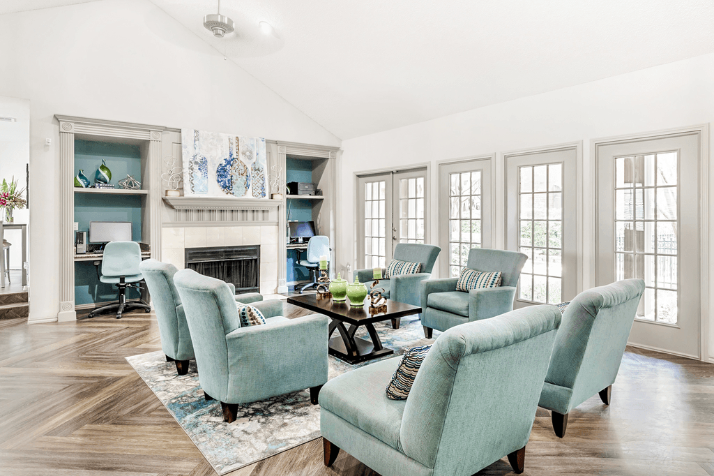 Clubhouse interior with upholstered chairs, accent rug, coffee table, vaulted ceiling, fireplace with mantle and computer desks with chairs and computers