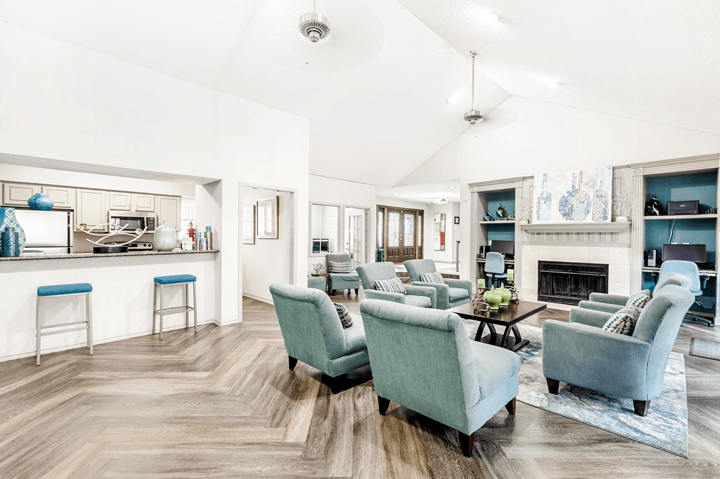 Clubhouse interior and kitchen with upholstered chairs, accent run, coffee table, fireplace, business center, vaulted ceiling and ceiling fans