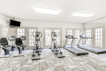 Fitness center with cardio machines, many windows and wall mounted television