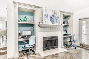 Clubhouse interior and business center with built in desks with computers and chairs with fireplace in between and wood style flooring