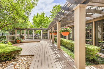 Clubhouse exterior patio with pergola, wrought iron tables and chairs with native landscape