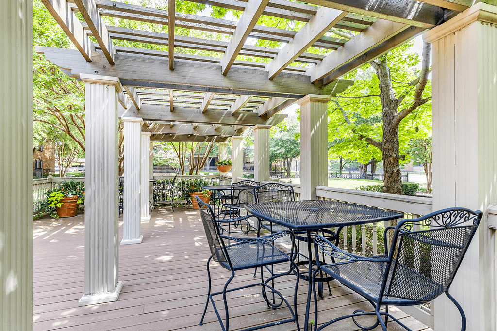 Clubhouse exterior patio with pergola, wrought iron tables and chairs with native landscape