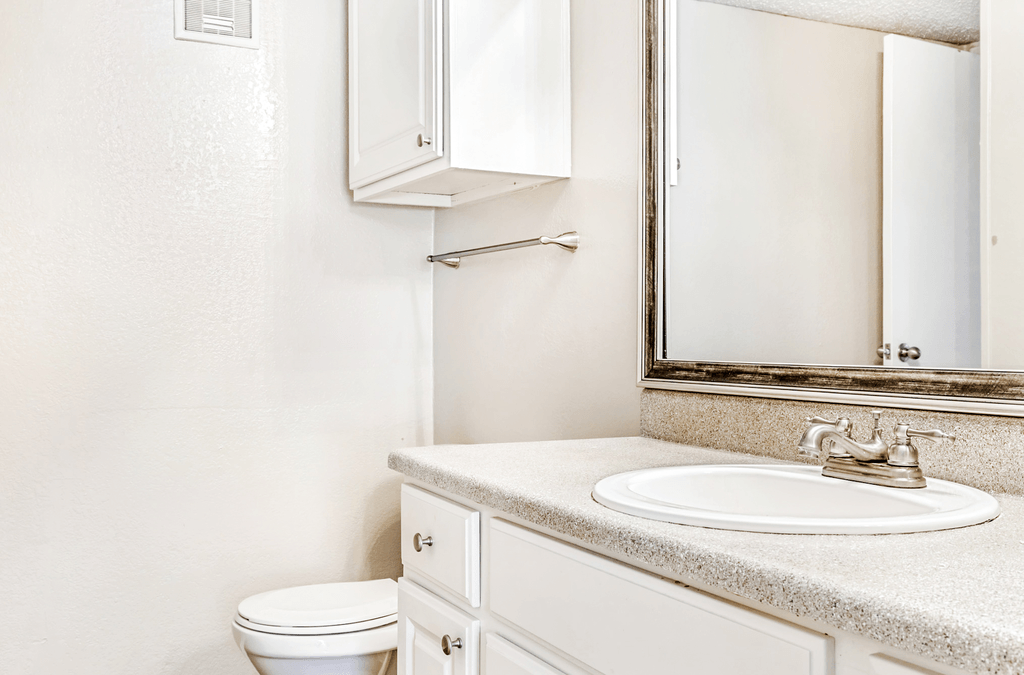 Bathroom with white cabinetry, granite inspired countertops, custom mirror vanity