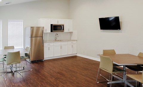 A kitchen with a refrigerator, microwave, and a dining table with chairs.