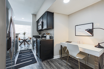 kitchen with black cabinets, hardwood-style flooring, and desk area