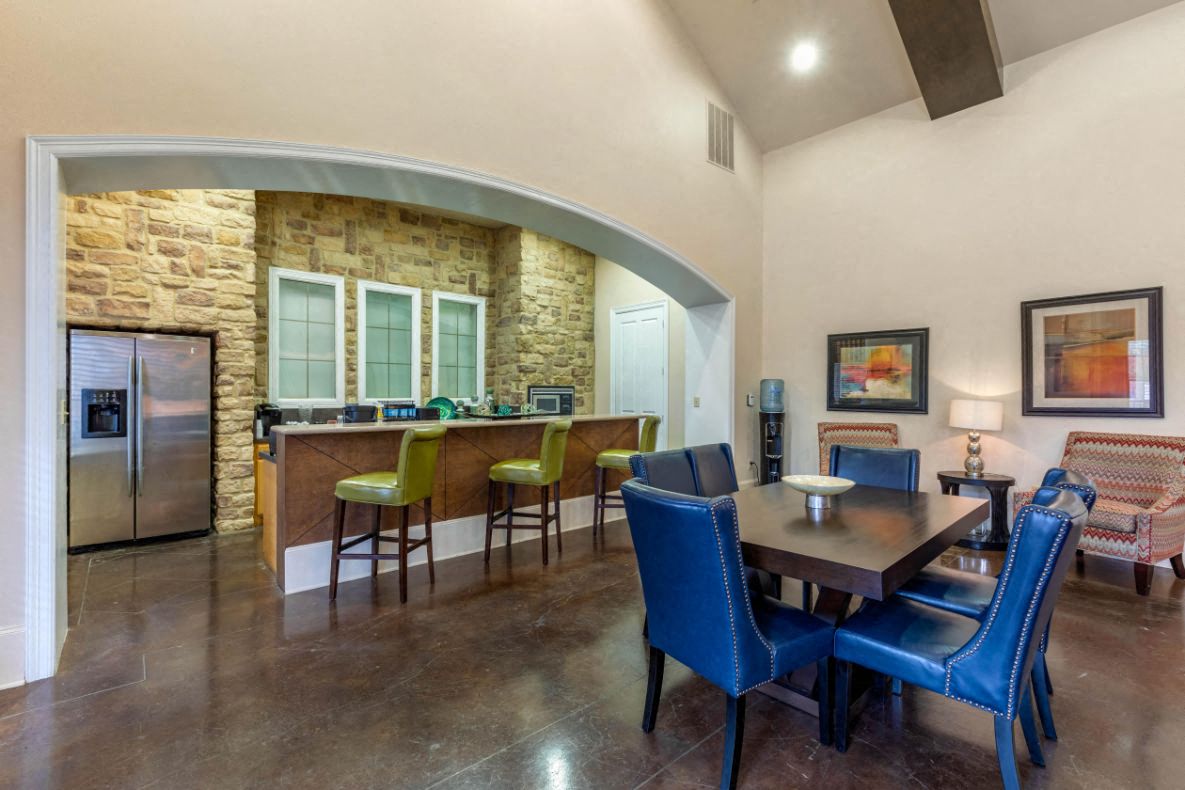 A kitchen with a stone wall and a dining table with blue chairs.