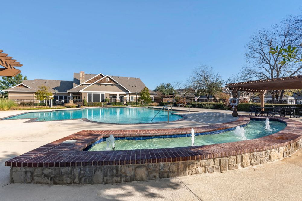 A large outdoor swimming pool with a waterfall feature in the middle.