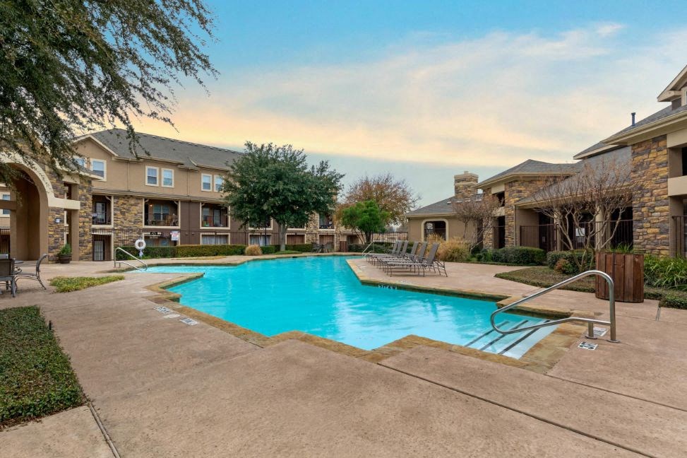Swimming pool with tanning deck, clubhouse exterior, green trees, and clubhouse in the background