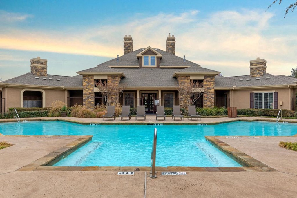 Swimming pool with tanning deck and clubhouse exterior in the background