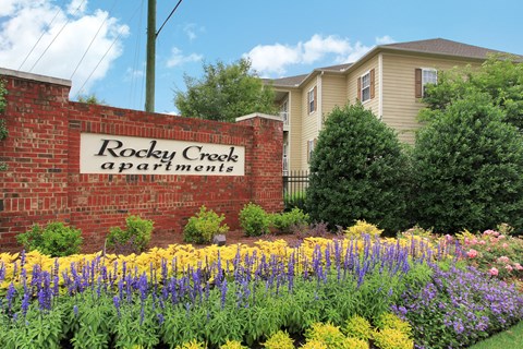 A sign that says Rocky Creek Apartments is in front of a building.