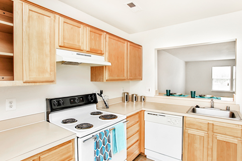 A kitchen with a white stove top oven and white dishwasher.