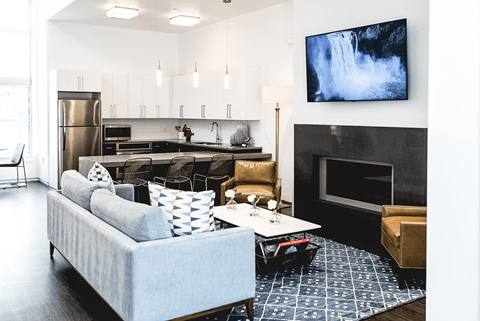 A modern living room with a grey couch and a television mounted on the wall.