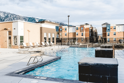 A swimming pool in front of a building with a mountain in the background.