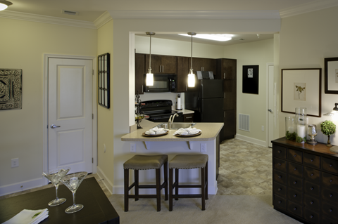 A kitchen with a bar stool and a table with two martini glasses on it.
