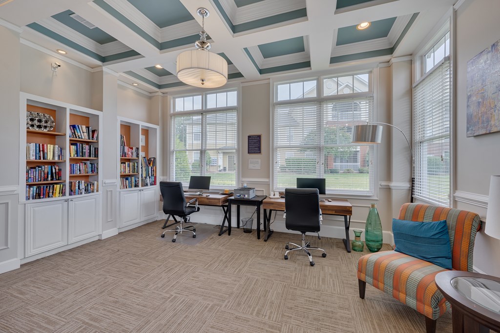 A room with a desk, chairs, and bookshelves.