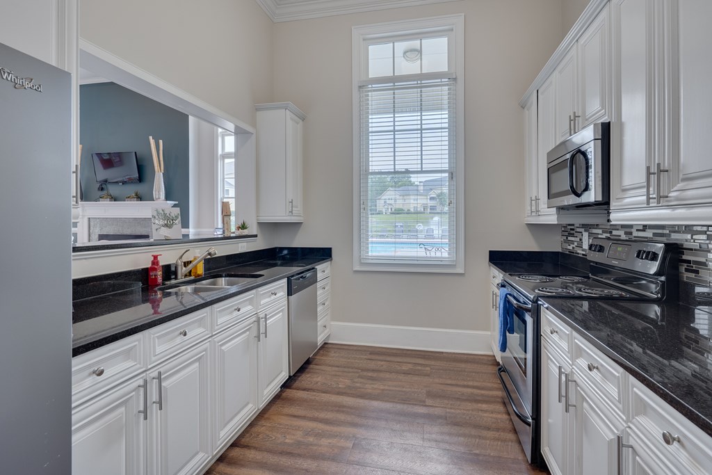 A kitchen with white cabinets and black countertops.