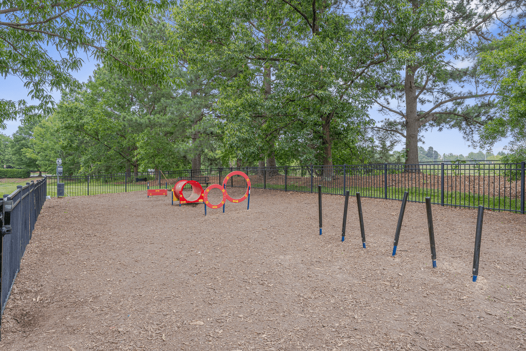 A playground with a red swing set and blue poles.