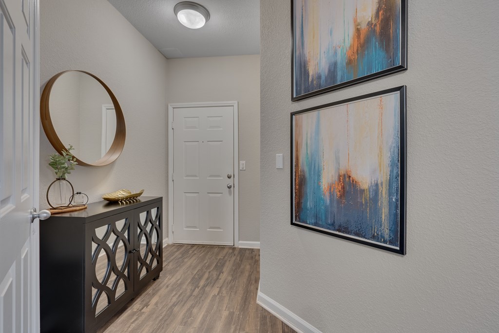 A hallway with a black railing and two framed artworks on the wall.