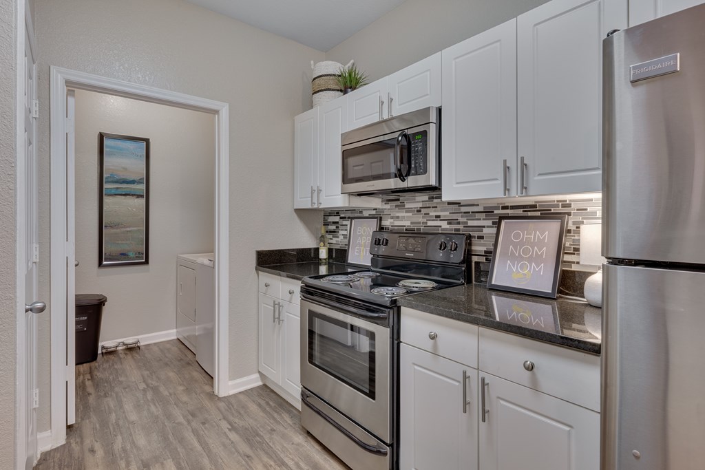 A kitchen with white cabinets and a stainless steel refrigerator.