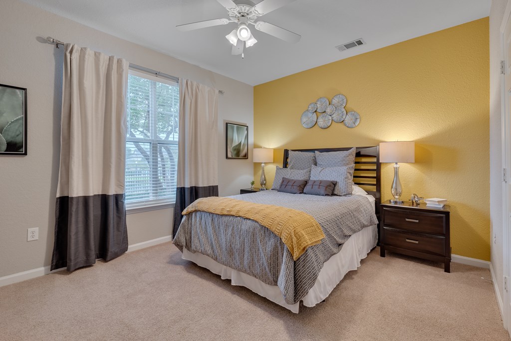 A bedroom with a bed, nightstand, and window.