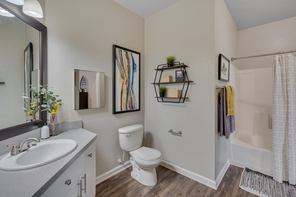 A bathroom with a white toilet, sink, and shower area.
