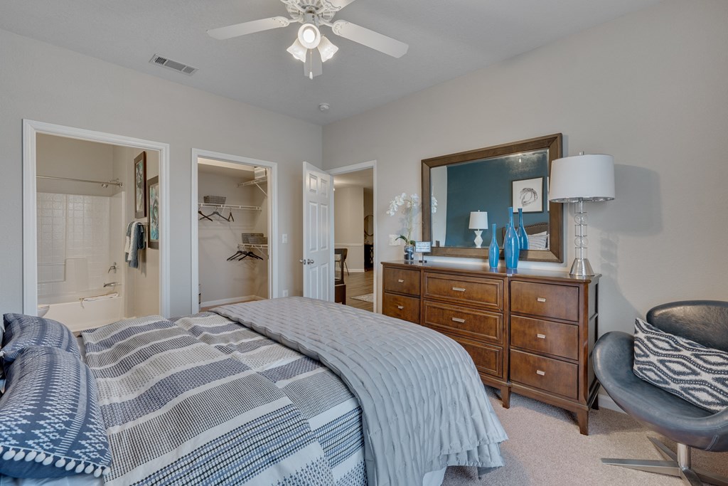 A bedroom with a bed, dresser, chair, and mirror.