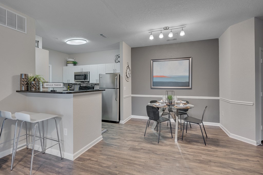 A kitchen with a bar area and a dining table with chairs.