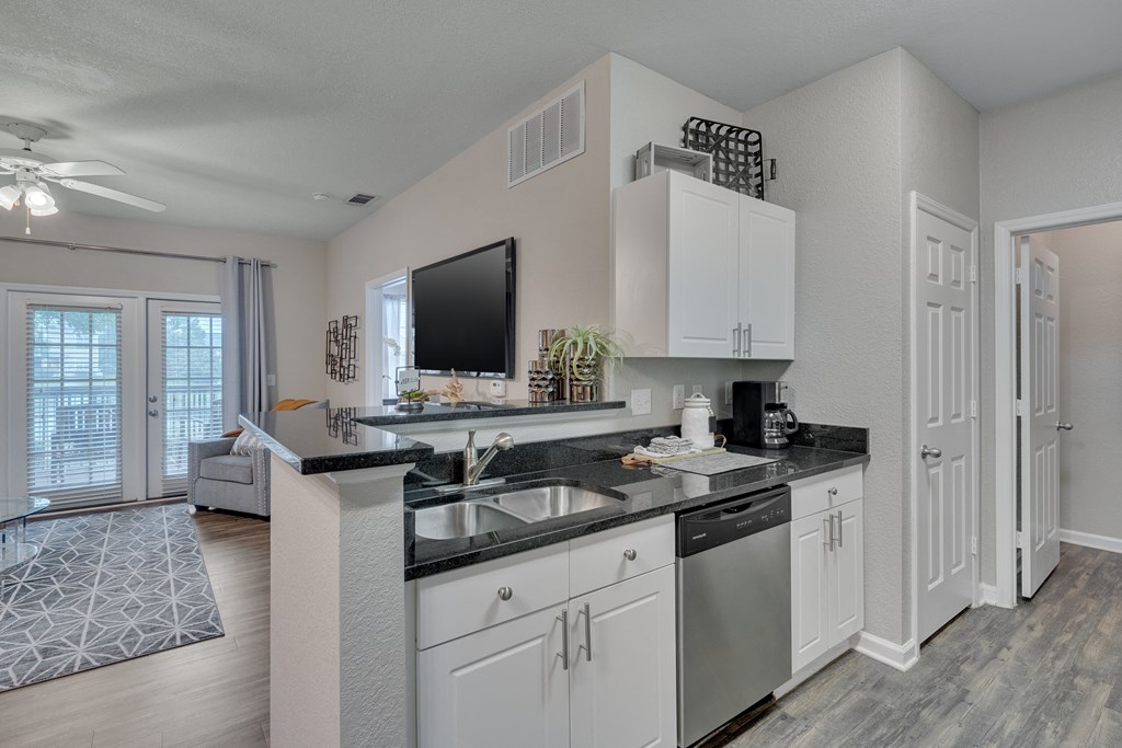 A modern kitchen with white cabinets and a black countertop.