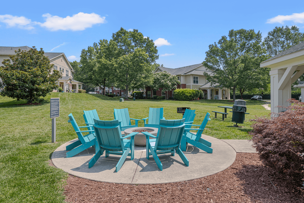 A set of green chairs and a table are arranged in a circle on a concrete slab.