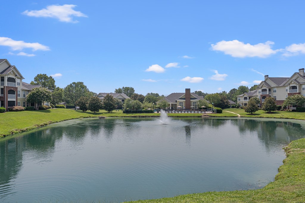 A fountain in the middle of a lake surrounded by apartment buildings..