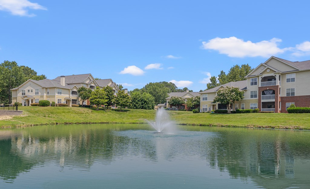 A fountain in the middle of a lake surrounded by houses.