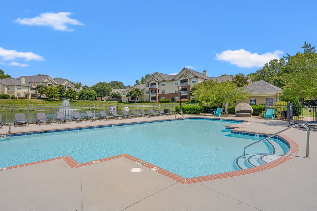 A large swimming pool surrounded by a fence and chairs.