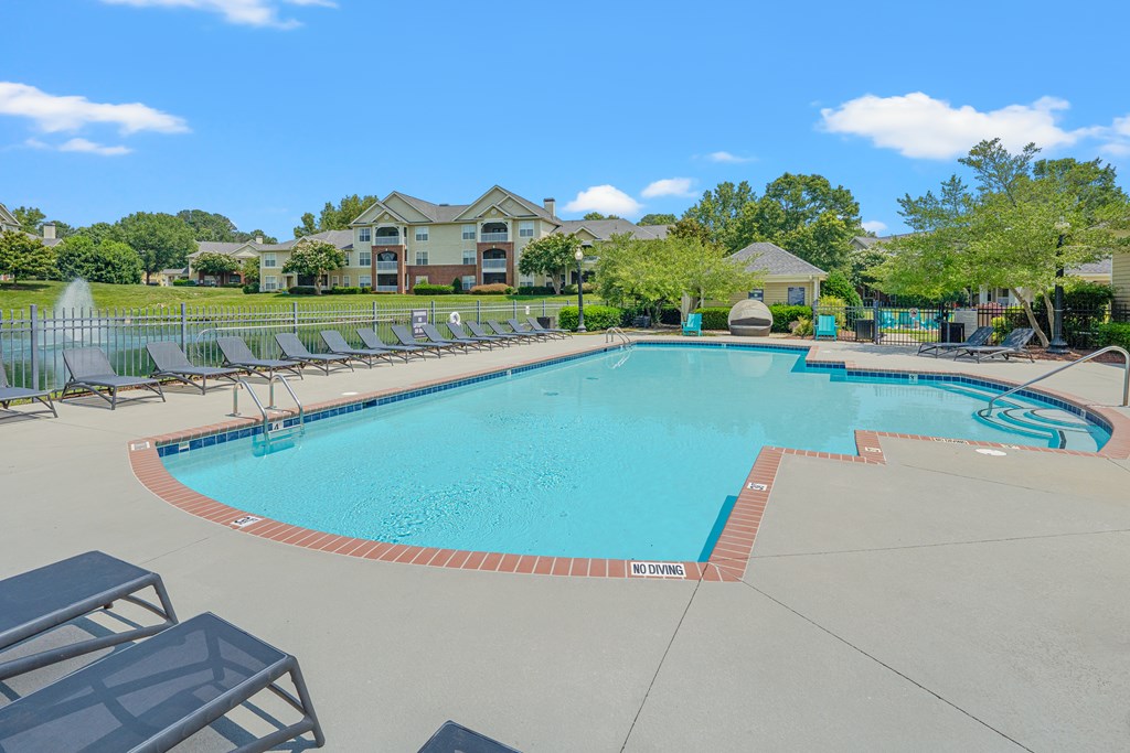 A large swimming pool surrounded by lounge chairs and trees.
