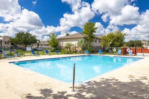 A large swimming pool with a blue tinted water and a brown pole in the middle.