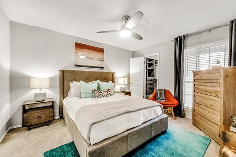 bedroom with bed, end tables and dresser by the window