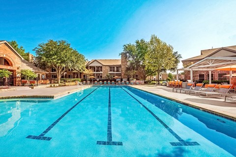 Swimming Pool and Sun Deck with Lounge Chairs with Trees and Building Exteriors in the Background