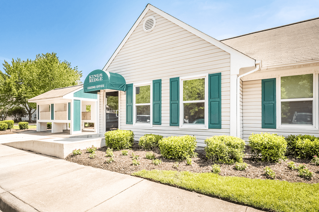 a white building with green shutters and a green awning