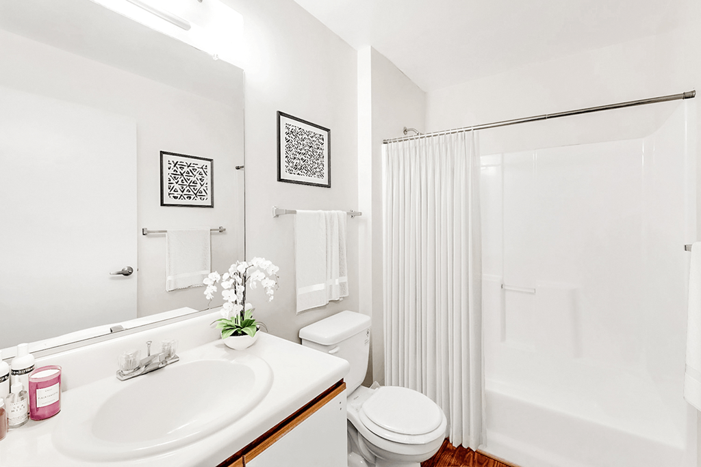 a bathroom with a white sink and toilet and a white shower curtain