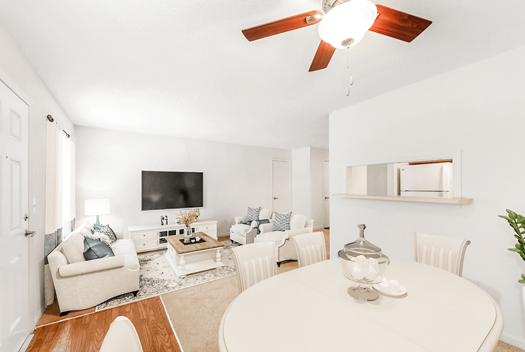 a living room with a white table and chairs and a flat screen tv on the wall