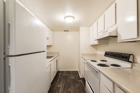 A white refrigerator is in a kitchen with a stove and cabinets.