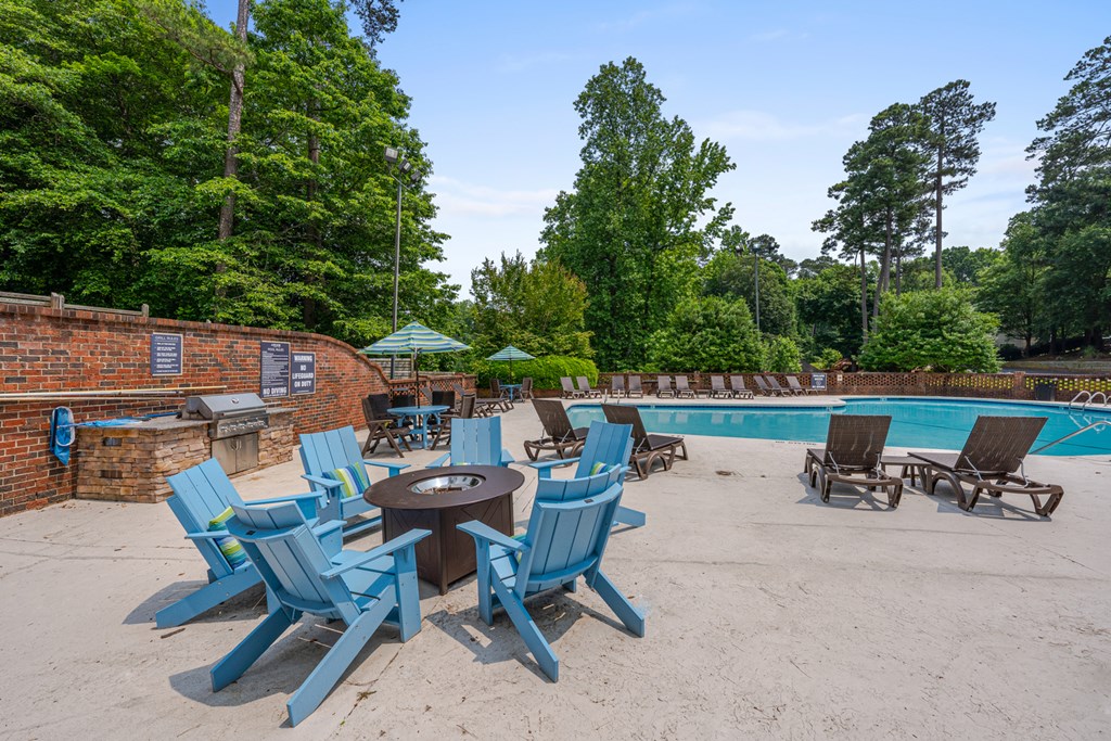 A poolside area with blue chairs and a fire pit.