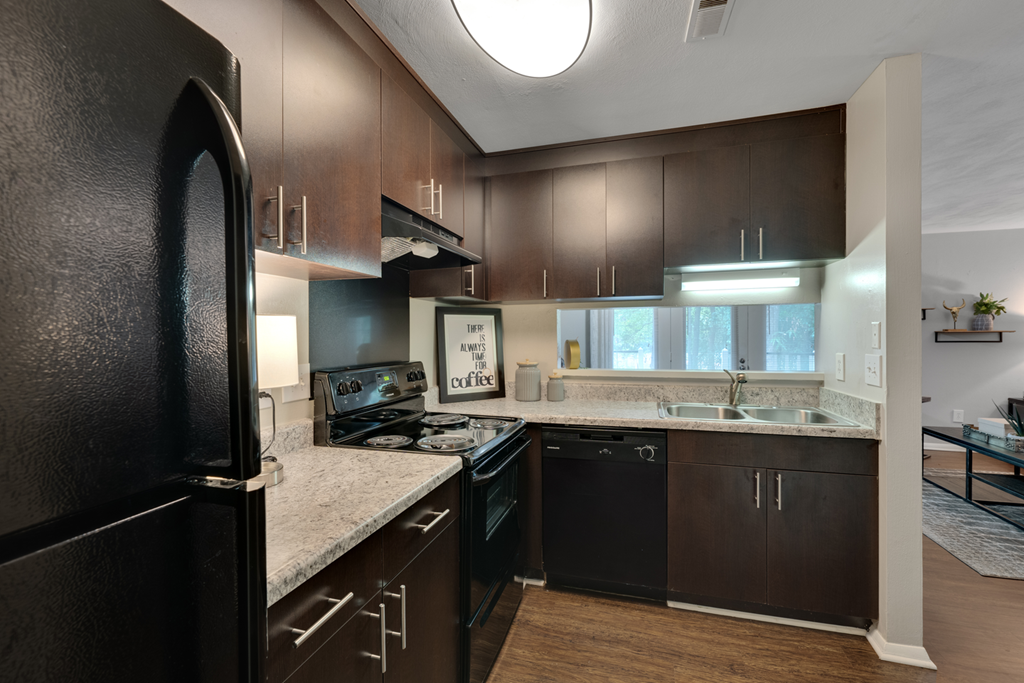 A kitchen with dark brown cabinets and black appliances.