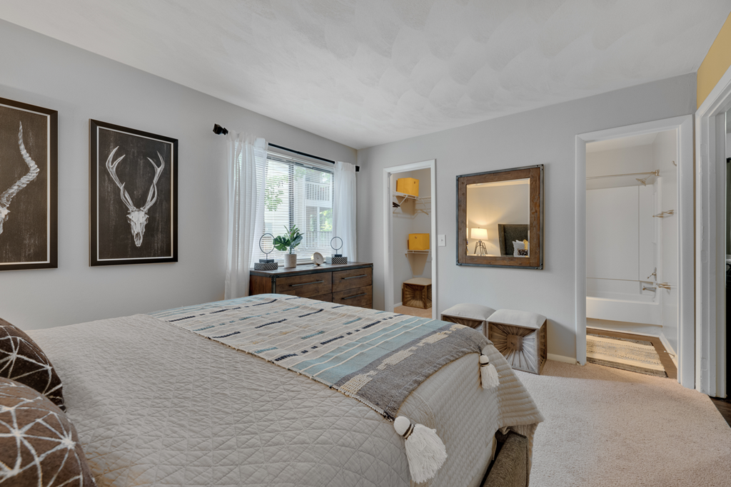 A bedroom with a large bed and a painting of a deer head on the wall.